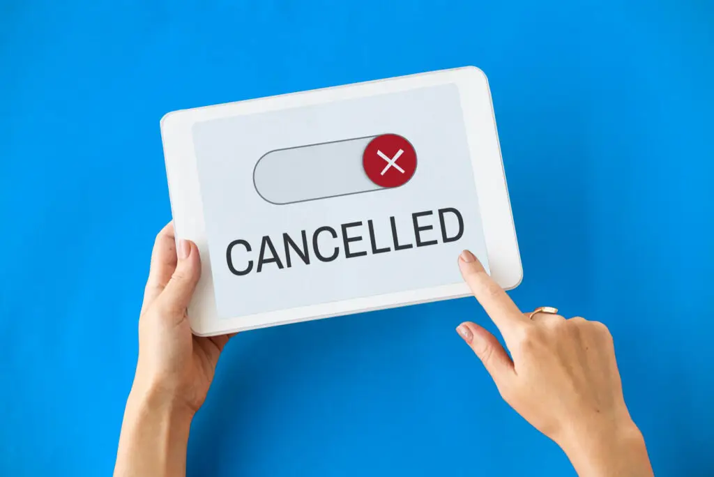 Hand pressing a switch labeled Cancelled on a blue background