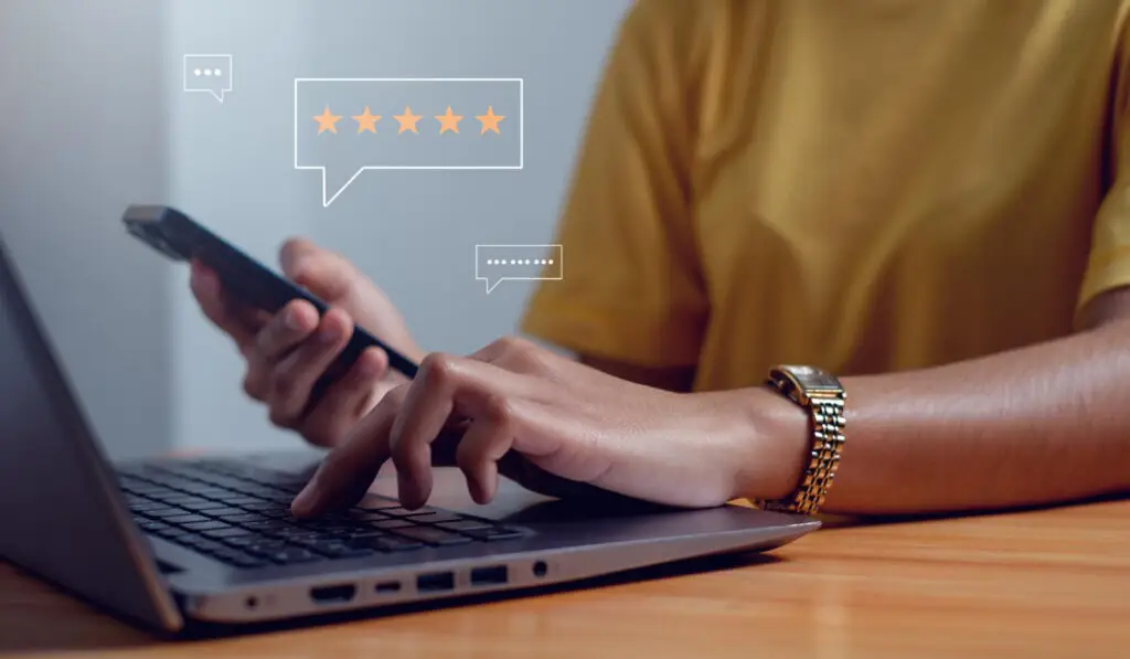 Person typing on a laptop next to a five-star review rating graphic